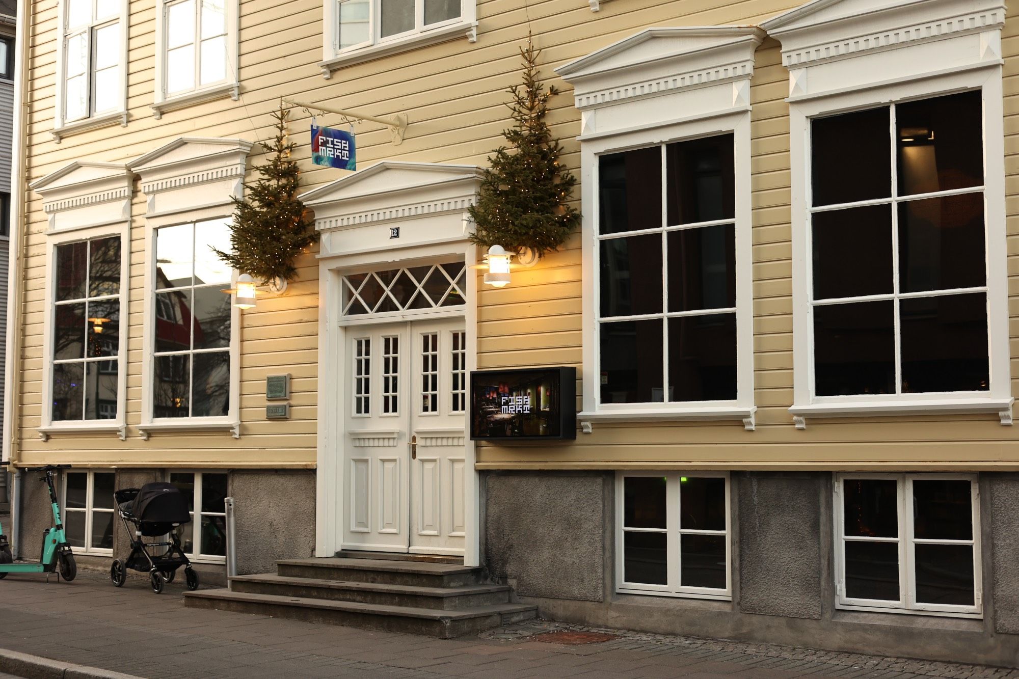 Building with light yellow siding and white accents, the outside of a restaurant called Fishmrkt in Reykjavik